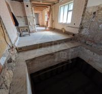 Interior of a family house with an exposed ceiling and raw walls under renovation.