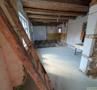 The interior of a family house with a wooden ceiling, old wallpaper, and a ladder.