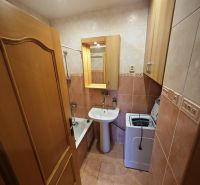 A bathroom in a 3-room apartment with a bathtub, sink, and washing machine.