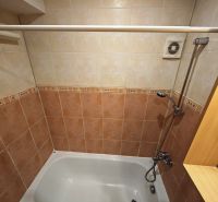 A bathroom with a bathtub and tiles in a 3-room apartment, a decent space for relaxation.