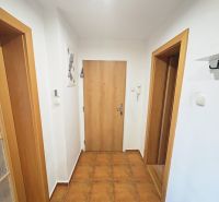 A hallway in a 3-room apartment with ceramic tiles, white walls, and wooden doors.