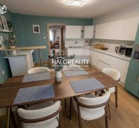 A kitchen in a family house with white cabinets, a wooden decor floor, and a dining table.