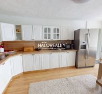 A kitchen in a family house with white cabinets, a refrigerator, and a wooden-patterned floor.