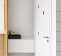 White interior of commercial space with a sink and doors.