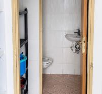 A bathroom in commercial premises with a toilet and a sink, simple tile design.