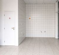 Commercial space with light flooring, white tiles, and wooden decor on the wall.