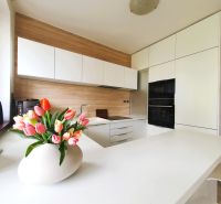 White kitchen with wood decor and tulips in a 3-room apartment.