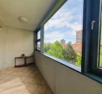 A glazed loggia in a 3-room apartment with a view of greenery and the city panorama.