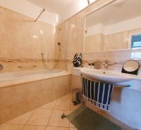 A bathroom with a bathtub, sink, and tiles in a 3-room apartment.