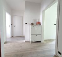 A hallway with white furniture and a wooden decor floor in a 3-room apartment.