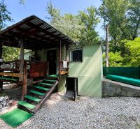 A wooden terrace of the cottage in Gabčíkovo surrounded by greenery and a gravel area.