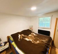 A cottage with a wooden decor floor, a bed, and a nightstand, simple bedroom design.