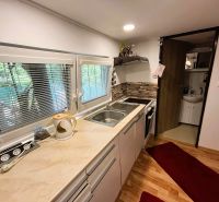 A kitchen in a cottage with a wood-patterned floor, a stove, and wooden decor.