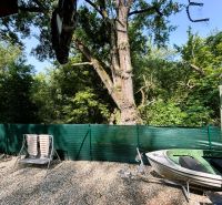 The yard of the cottage in Gabčíkovo with a deck chair, a boat, and a forest scene.