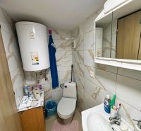 A bathroom with tiles and a boiler offers basic hygiene supplies and storage space.