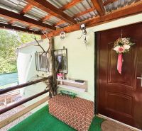 A cottage in Gabčíkovo with a decorative entrance, railing, and seating area near a green space.