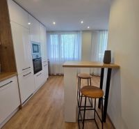 A kitchen with white cabinets, a wooden decor floor, high chairs in a 3-room apartment.