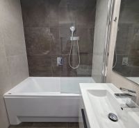 A bathroom in a 3-room apartment with a bathtub, a shower screen, and a modern sink.