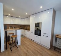 A kitchen in a 3-room apartment with bar seating and a floor with a wooden decor.