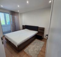 A bedroom with a bed and a wooden decor floor in a 3-room apartment.