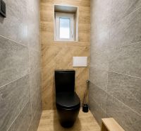 A toilet in a family house with a black toilet and a floor with a wooden decor.