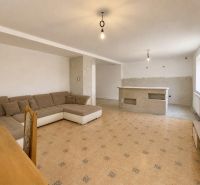 Living room in a family house with a large sofa, TV, and dining table.