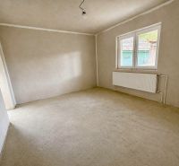 An empty room with a window and a white radiator in a family house.