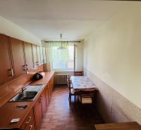 A kitchen in a 3-room apartment with a wooden decor floor, light furniture, and a dining table.