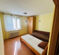 A room in a 3-room apartment with a bed, a sofa, and a floor with a wooden decor.