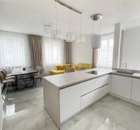 A kitchen in a 3-room apartment with a yellow sofa and a dining table.