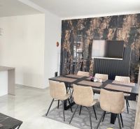 Dining room with a table and six chairs, wooden decor flooring, TV on the wall.