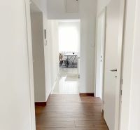 The hallway of the 3-room apartment with a wooden decor floor leads to the dining room.