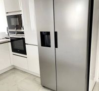 A kitchen in a 3-room apartment with a stainless steel refrigerator and ceramic tiles.