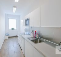 Office kitchen with light furniture and appliances, with a wood-patterned floor.