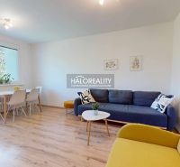 Living room in a three-room apartment with a wooden decor floor and light furniture.