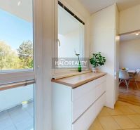 A kitchen in a 3-room apartment with white furniture and a view of the surroundings.