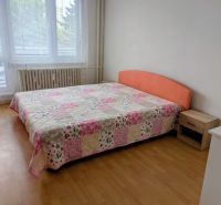 Bedroom with a bed and a patchwork bedspread in a 2-room apartment, floor with a wooden decor.