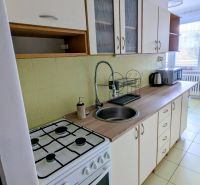 A kitchen in a 2-room apartment with a stove, sink, and kitchen cabinets.
