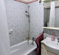 Bathroom in a 2-room apartment with a bathtub, sink, and ceramic tiles.