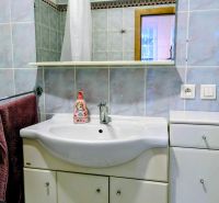 A bathroom in a 2-room apartment with a sink, mirror, and blue tiles.