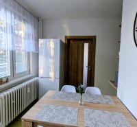 Dining area in a 2-room apartment with a wooden table and white chairs.