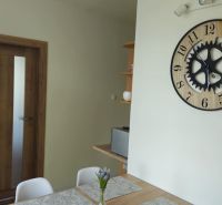 Interior of a 2-room apartment with a clock on the wall, wooden doors, and a table.