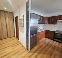 A kitchen in a 2-room apartment with wooden furniture and a built-in wardrobe.