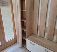 A wooden hanger with storage space by the window in a 2-room apartment.