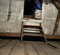 The attic of the family house with wooden stairs and a package.