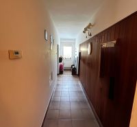 A hallway in a family house with tiles and wooden wall paneling.