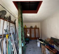 A storage space with tools in a family house, with access to the attic via a ladder.
