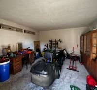 A garage in a family house with various tools and a ride-on lawnmower.