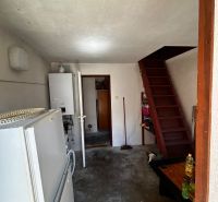 Interior of a family house with a refrigerator, boiler, and wooden stairs.