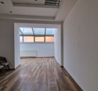 Interior of commercial premises with wood-patterned flooring and a row of chairs.